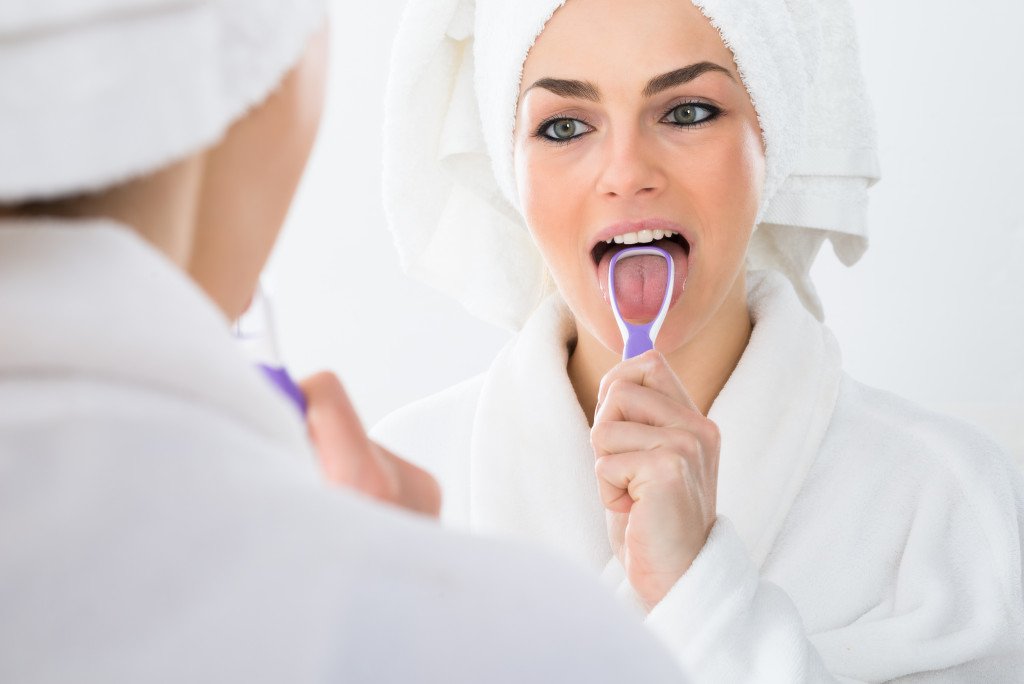 Close-up Of A Woman Looking In Mirror Cleaning Her Tongue