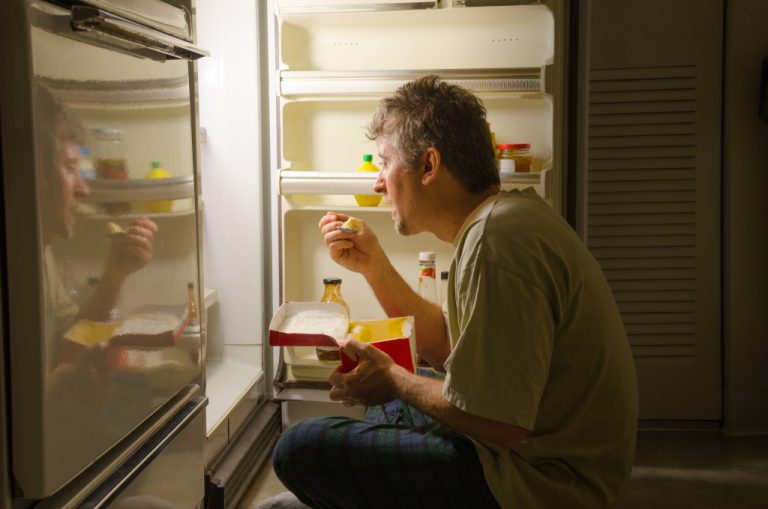 man binge eating in fridge