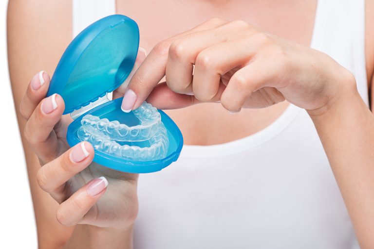 woman taking out clear aligners out of its casing