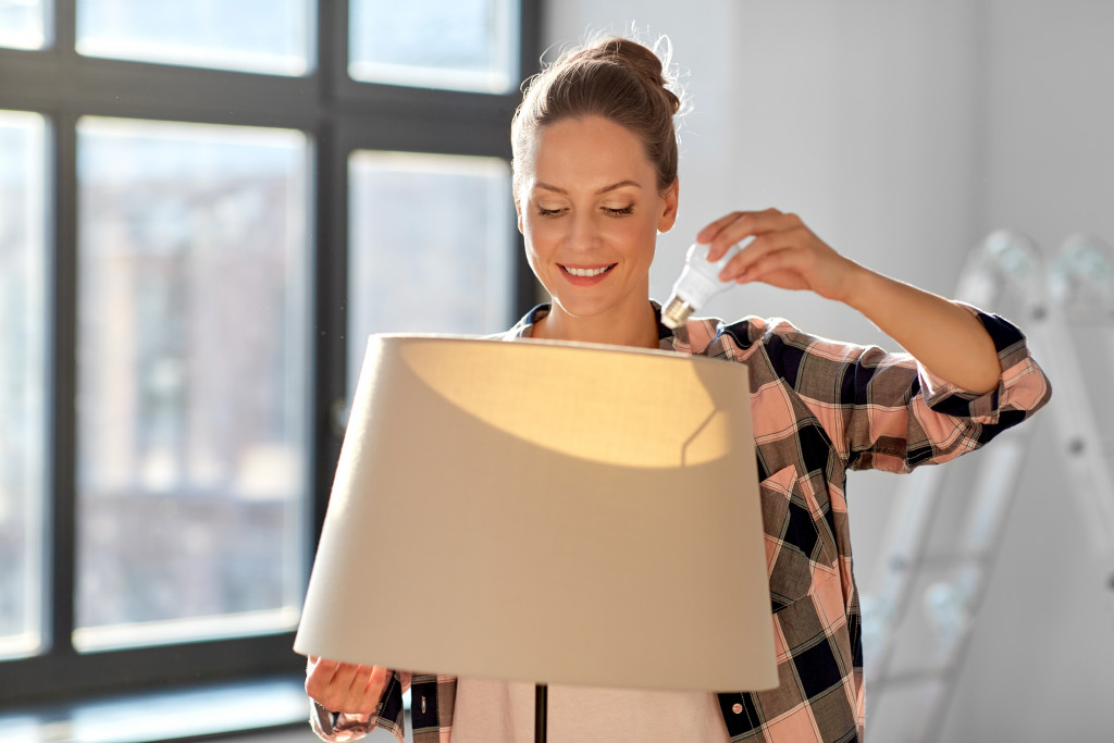 Woman changing light bulb in floor lamp at new home