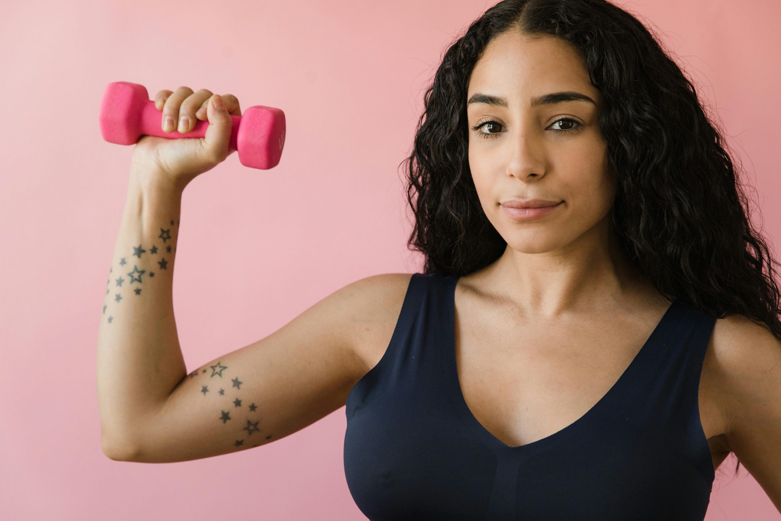 woman in athletic wear holding a pink dumbbell
