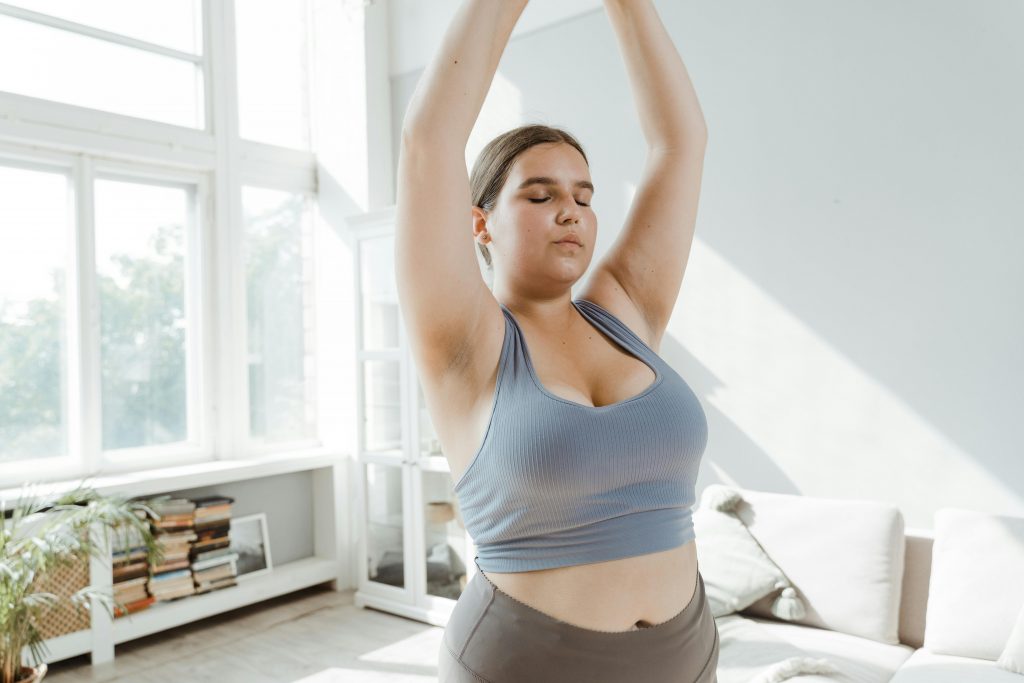 plus-size woman practicing yoga in a sunlit room