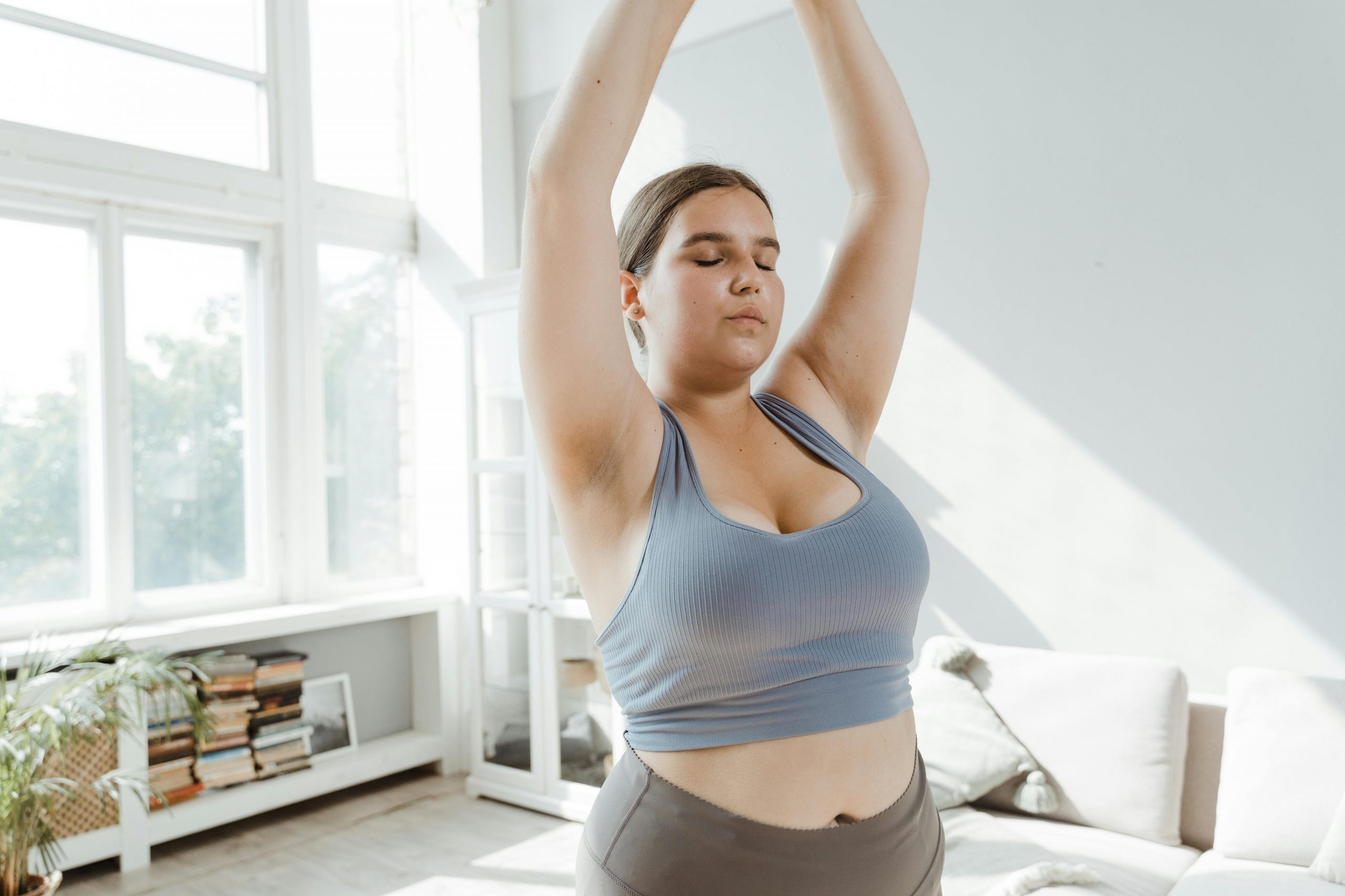 plus-size woman practicing yoga in a sunlit room